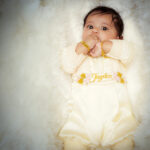 Baby in full cream baptism romper dress with floral embroidery and name “Jayden”
