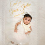 Baby girl wearing baptism dress and booties on personalized embroidered quilt