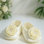Off-white satin baby baptism booties with rose and pearl embellishments