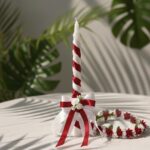 An elegant red and white spiral baptism candle and matching red floral crown set, handcrafted for a special occasion by Navin Creations in Kerala.