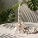 A chic rose gold and white spiral christening candle with a matching pearl and floral tiara, a custom-made baptism set by Navin Creations.