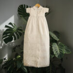 An elegant 2-in-1 heirloom christening outfit for a baby boy in ivory satin, displaying a traditional long gown with pintuck details and the matching short-sleeved romper set.