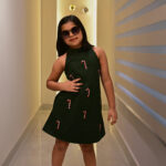 Girl wearing a green sleeveless dress printed with candy cane motifs