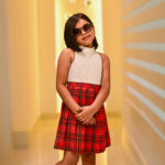 Girl wearing a white top with a red plaid Christmas skirt dress