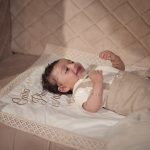 Baby boy wearing a personalised beige and ivory baptism outfit with bow tie and embroidered name.