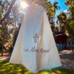 Back of an ivory baby boy baptism cape embroidered with a cross and personalised name.