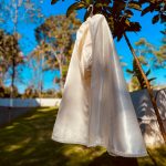 Ivory baby boy baptism cape displayed over a personalised satin christening romper.