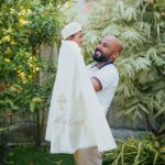 Father holding a baby boy wearing an ivory personalised christening cape with embroidered cross and name.