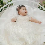 White pearl embellished baptism gown for baby girl with lace sleeves, floral embroidery and matching pearl headband.